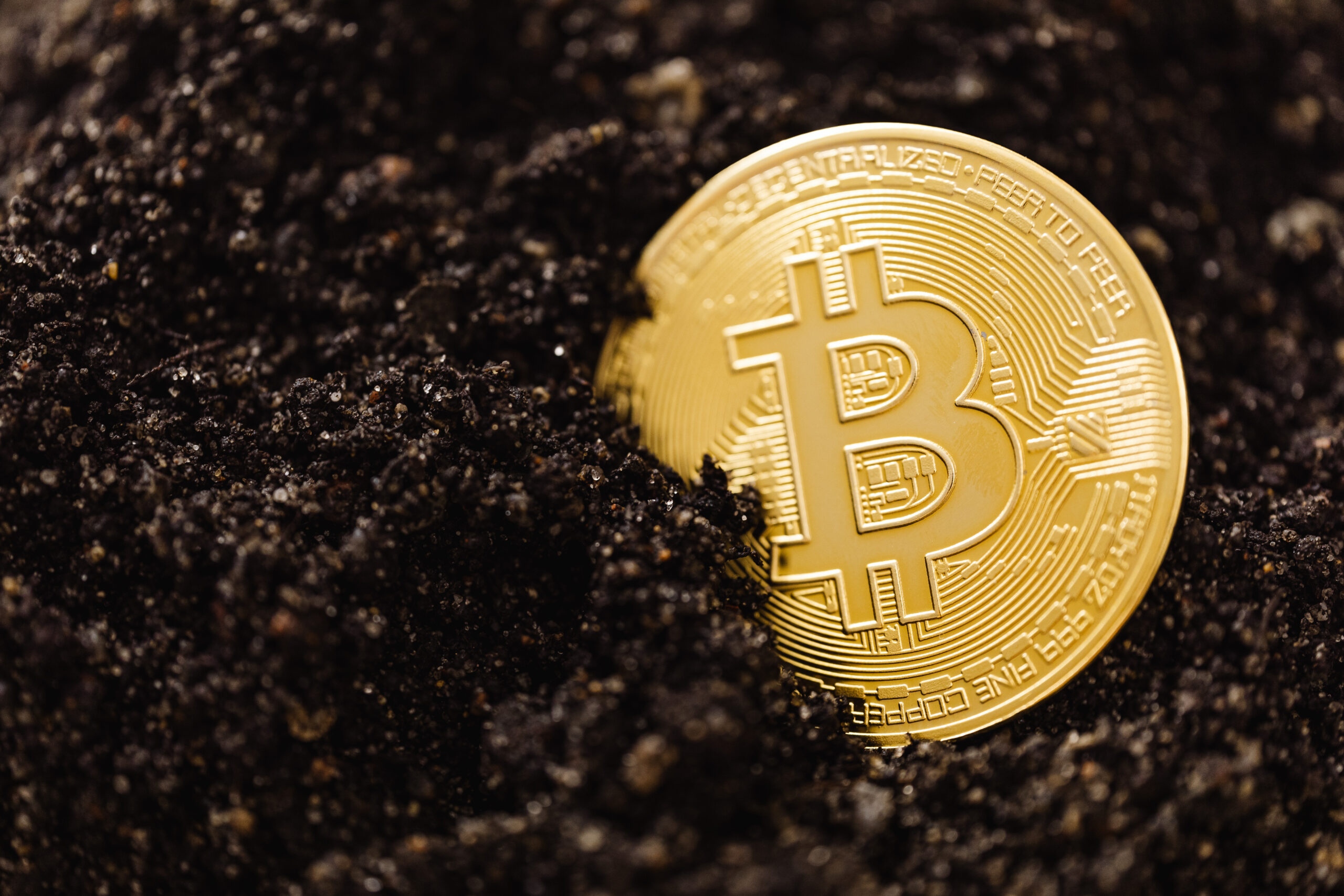 Close up shot of a bitcoin buried in the ground